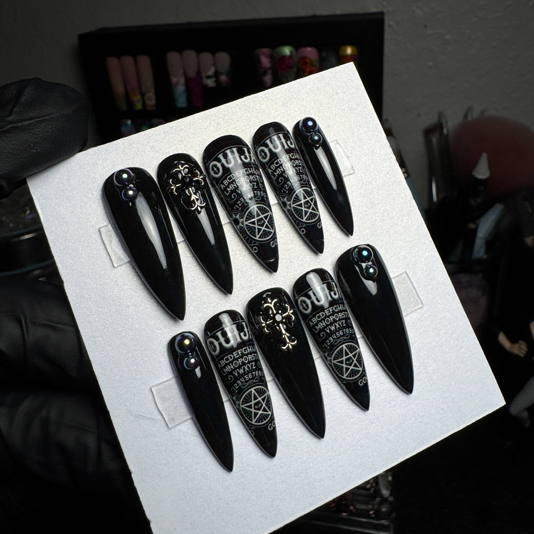 Black press-on nails with vintage ouija board lettering and symbols