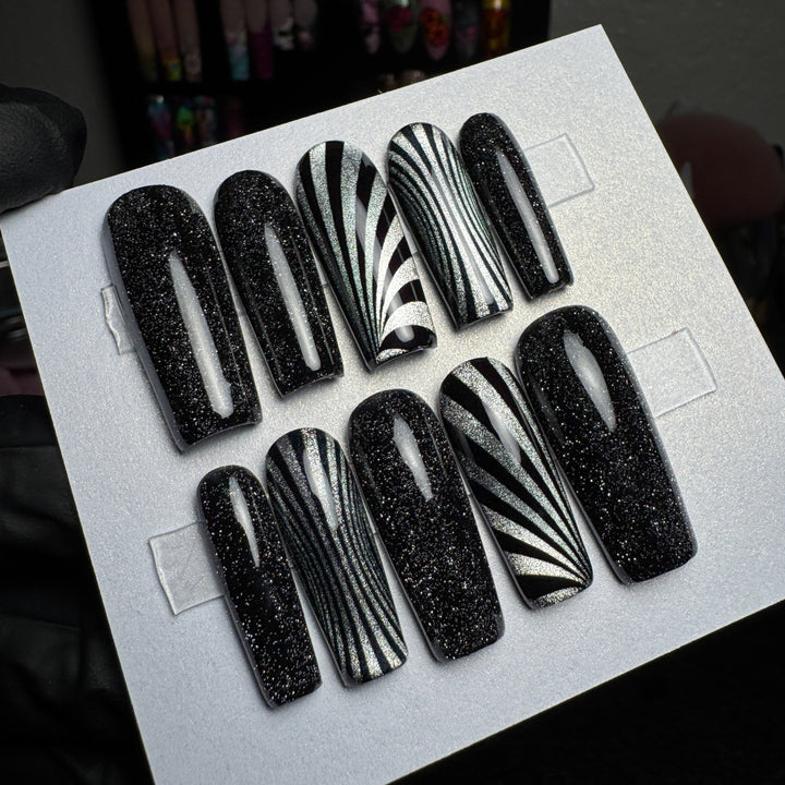 Black and silver press-on nails with optical stripe accent designs