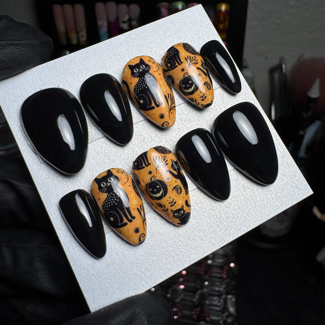 Orange Halloween press-on nails with spooky cat accent designs